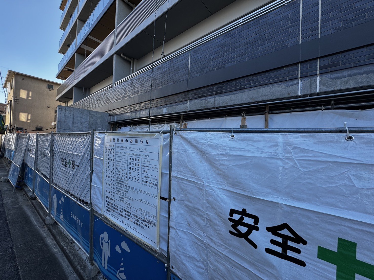 建築中のマンション外壁と建築計画のお知らせの掲示