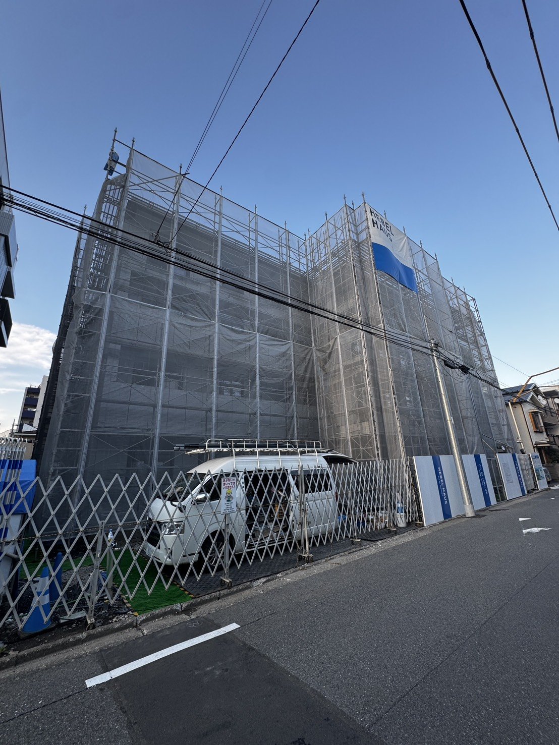 足場とシートに覆われた建築中のマンションを別角度から見た様子