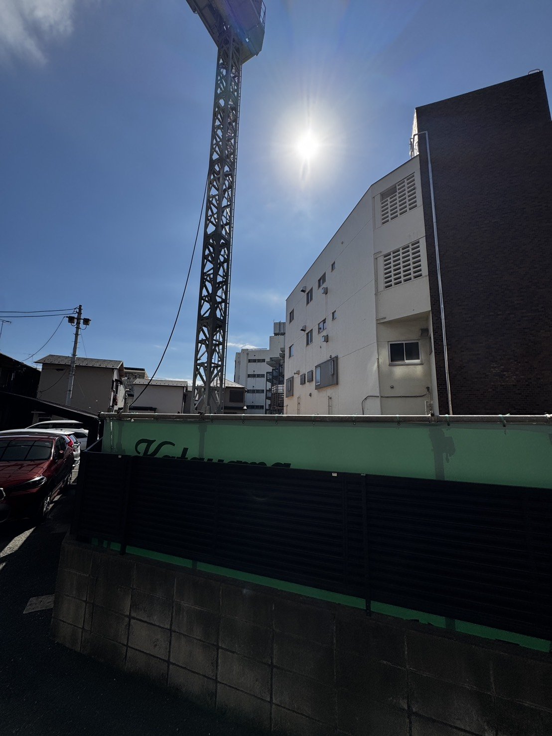 隣接する建物と上空のタワークレーン、日当たりの良さがうかがえる現地の様子